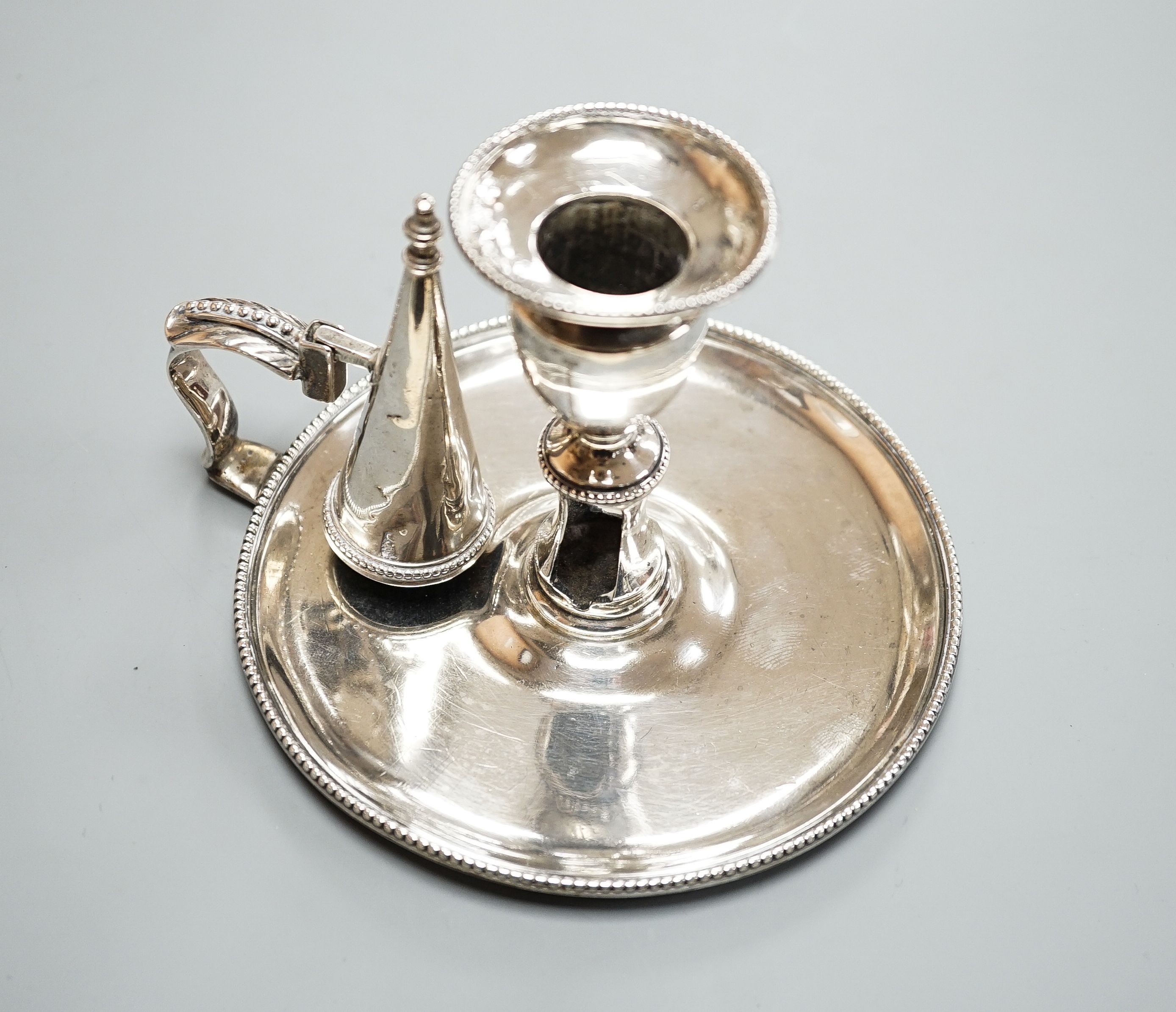 A George III silver chamberstick, by John Arnell, with beaded border and matching sconce and snuffer, London, 1784, diameter 12.8cm, 8oz (a.f.).